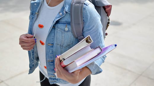 woman wearing blue denim jacket holding book