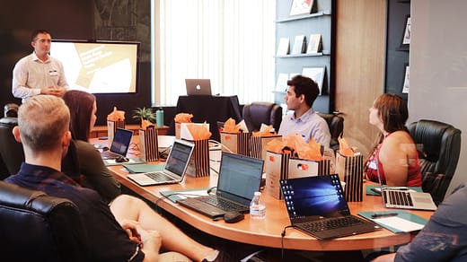 man standing in front of people sitting beside table with laptop computers