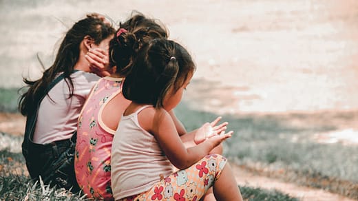 three children sitting on grass