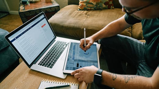 person holding pen and macbook air