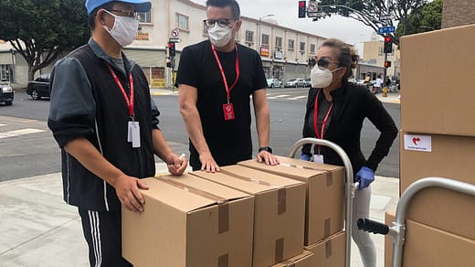 3 men in black polo shirt standing beside brown cardboard boxes