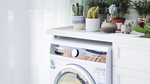 white front load washing machine beside white wooden cabinet