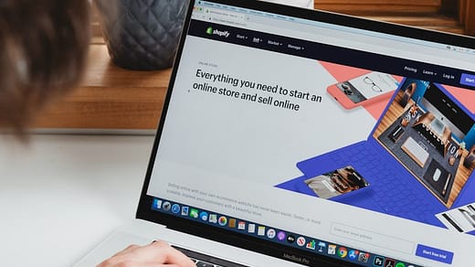 person using macbook pro on white table