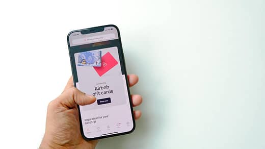 Close-up of a Man Holding a Smartphone Displaying a Shop with Airbnb Gift Cards