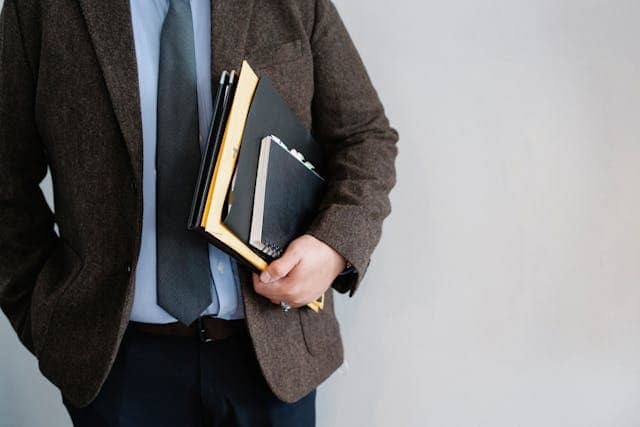 Man in suit and tie holding folders and documents